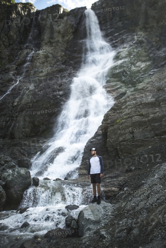 Man standing near Sofiyskiye Vodopady waterfall in Caucasus Mountains