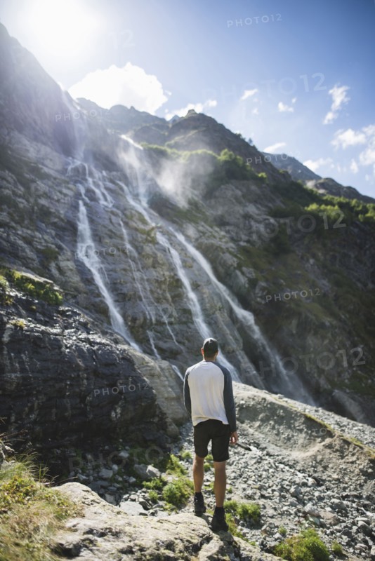 Man standing near Sofiyskiye Vodopady waterfall in Caucasus Mountains