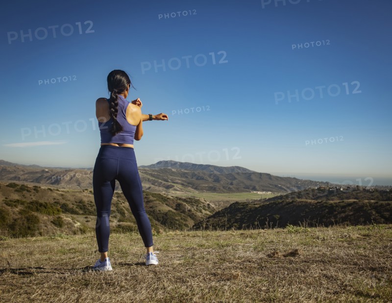 Rear view of woman stretching in landscape