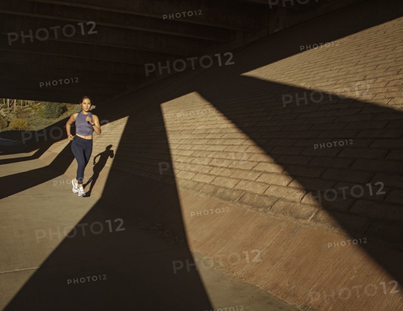 Woman jogging near brick wall in sunlight
