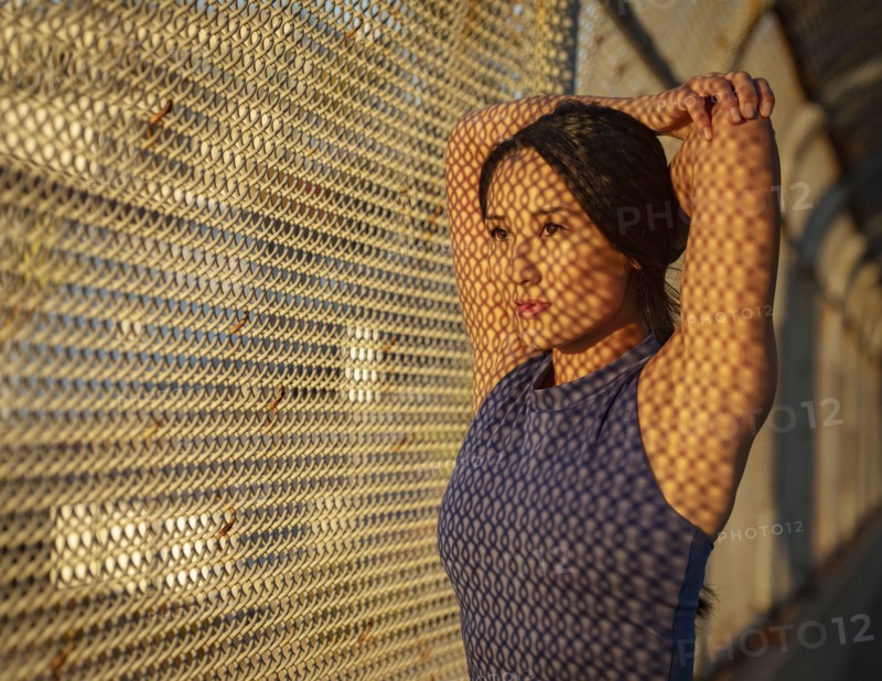 Athlete woman stretching at fence