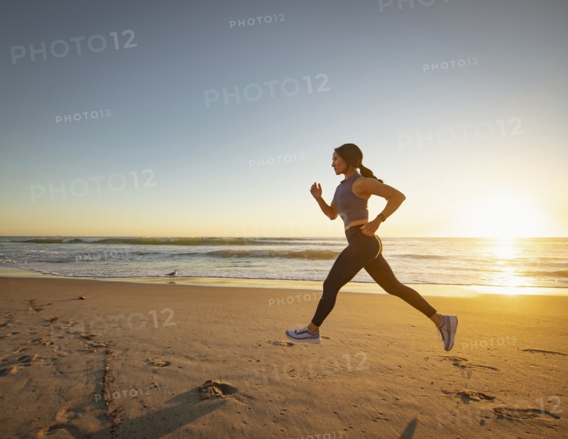 Woman jogging on beach at sunset