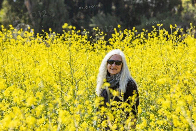Portrait of smiling senior woman in field of wild mustard