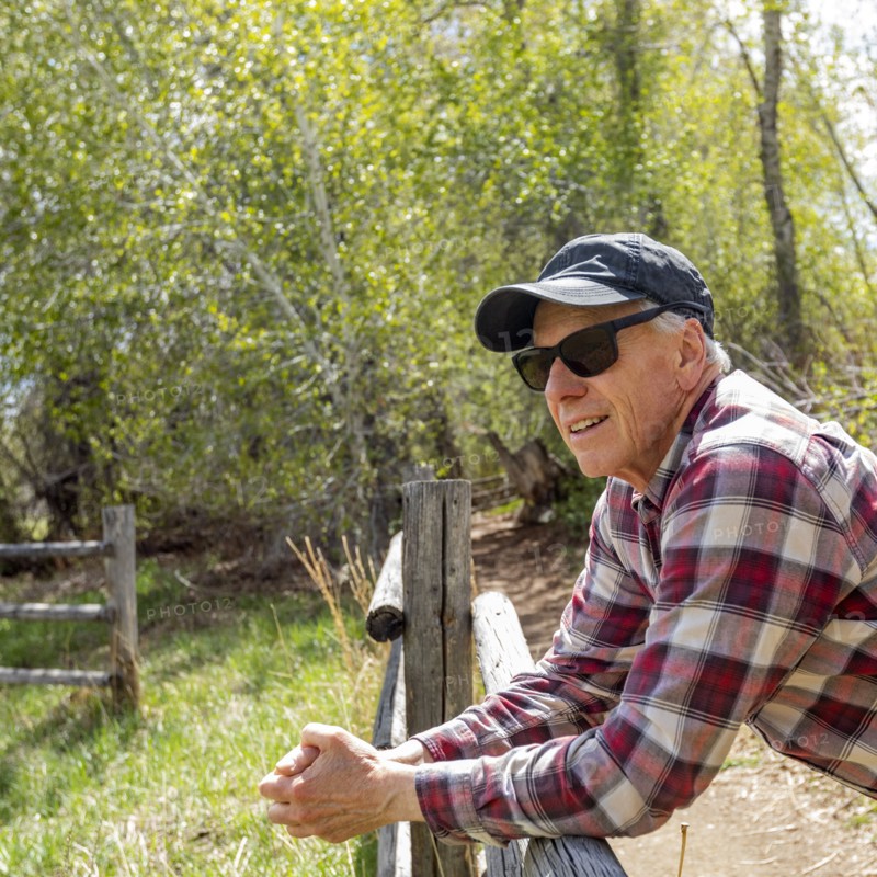 Senior farmer leaning on wooden fence near Sun Valley