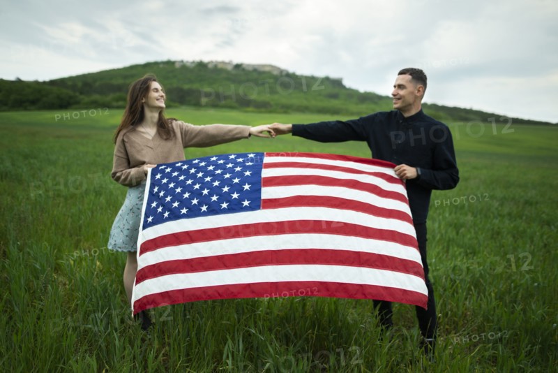 Young couple holding American flag in wheat field