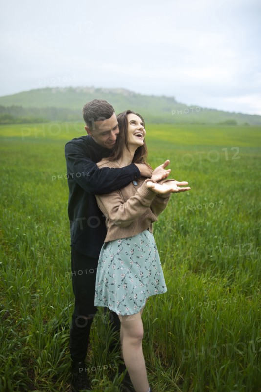 Young couple embracing in wheat field in rain