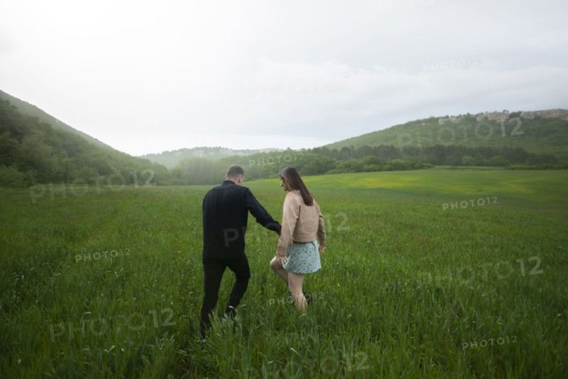 Rear view of young couple walking in wheat field in rain