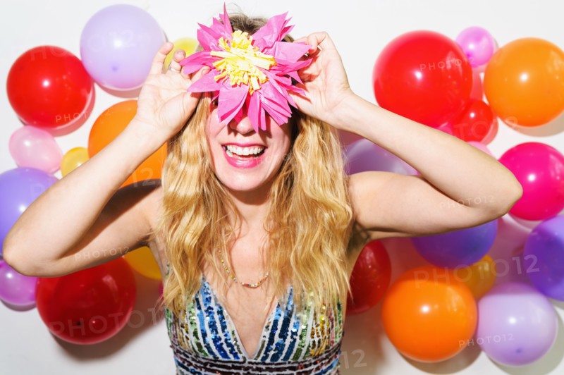Woman holding up tissue flower in front of balloon wall