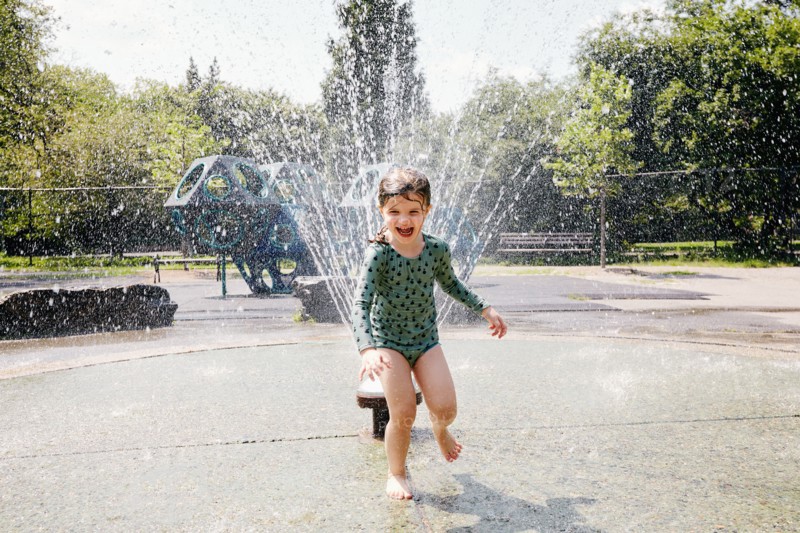 USA, New York, New York City, Girl playing next to water sprinkler on playground