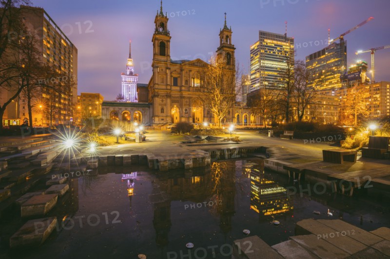 Poland, Masovia, Warsaw, Church and illuminated city skyscrapers reflecting in pond at night