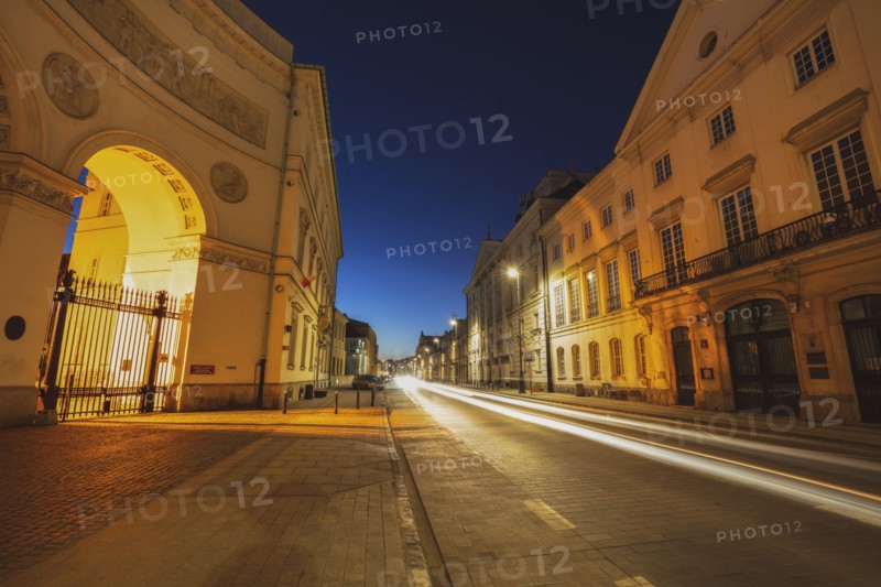 Poland, Masovia, Warsaw, Illuminated city street with historical buildings at night
