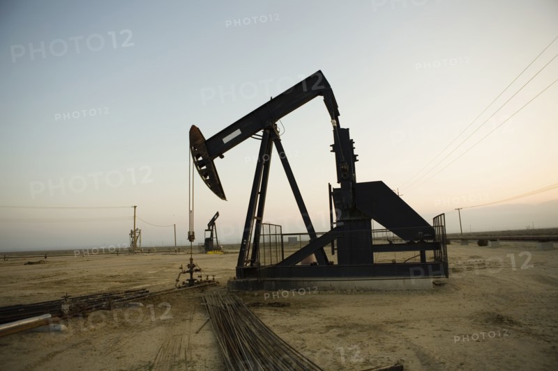 Silhouette of pump jack in oil field at sunset