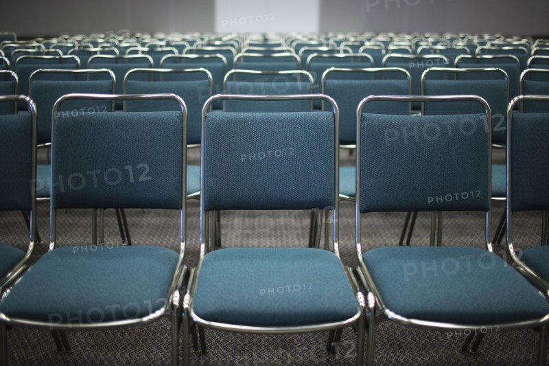 Rows of empty blue chairs in conference room
