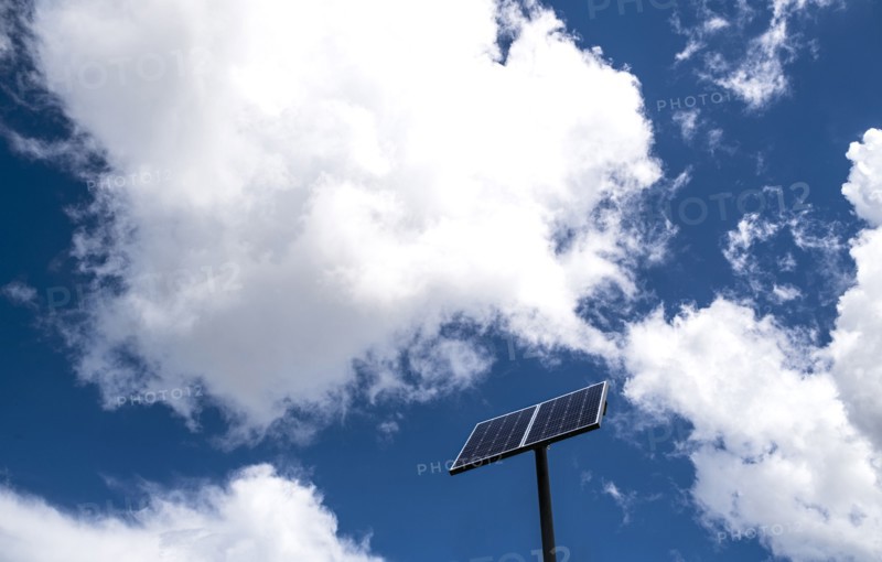 Solar panels against sky with white clouds
