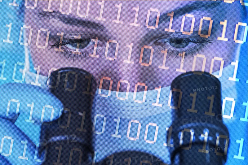 Close-up of female scientist in face mask looking int microscope