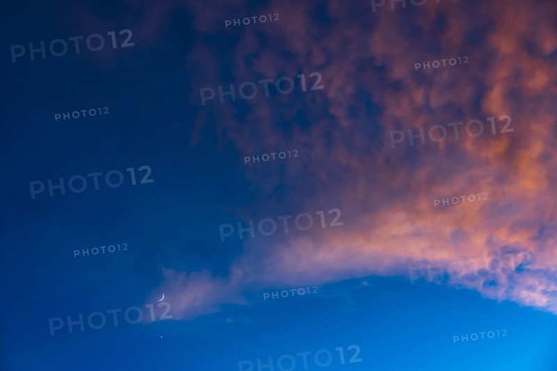 Crescent moon against blue sky with pink clouds