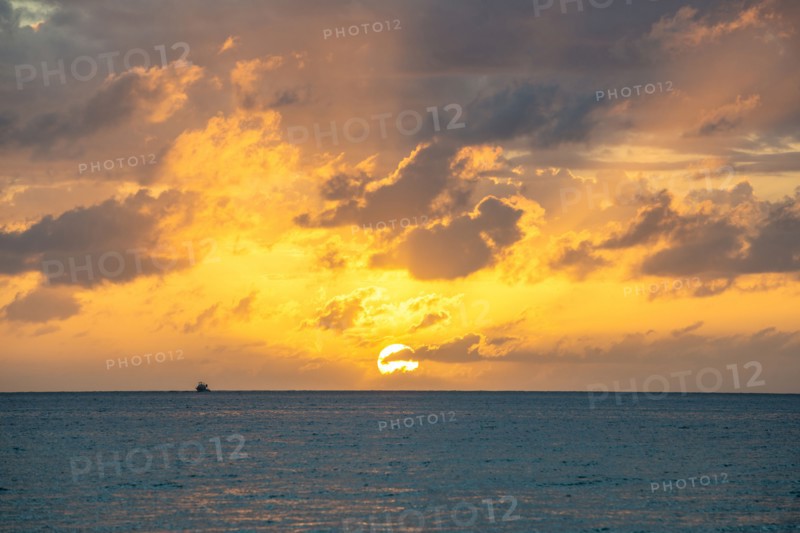 Dramatic sky at sunset over sea with fishing boat in distance