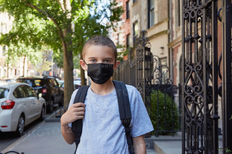 Portrait of Boy in face mask standing on sidewalk