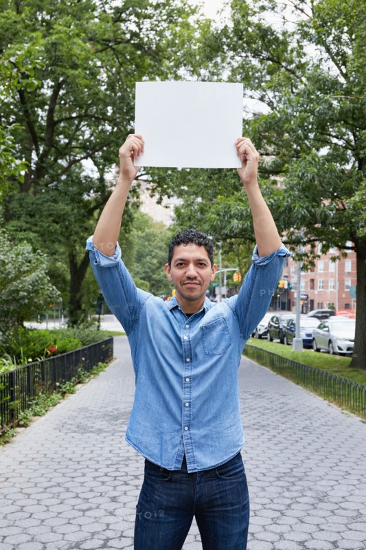 Portrait of man holding blank sign