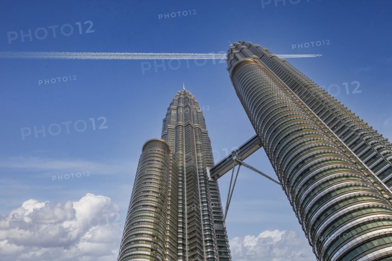 Commercial jet flying over Petronas Towers