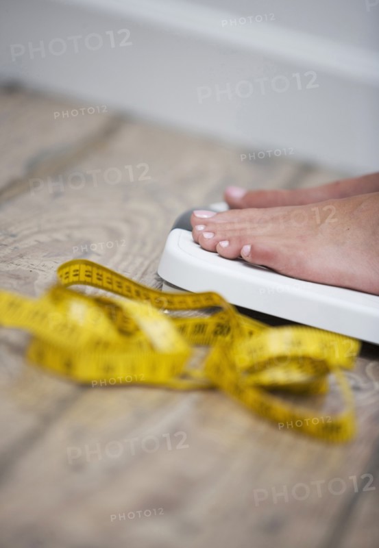 Tape measure next to woman standing on scale
