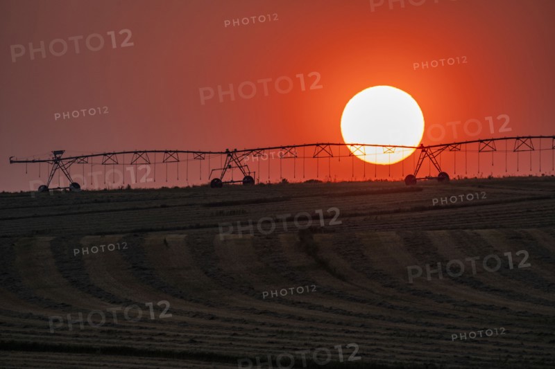 Irrigation equipment in field against setting sun