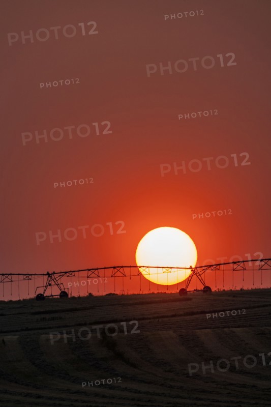 Irrigation equipment in field against setting sun