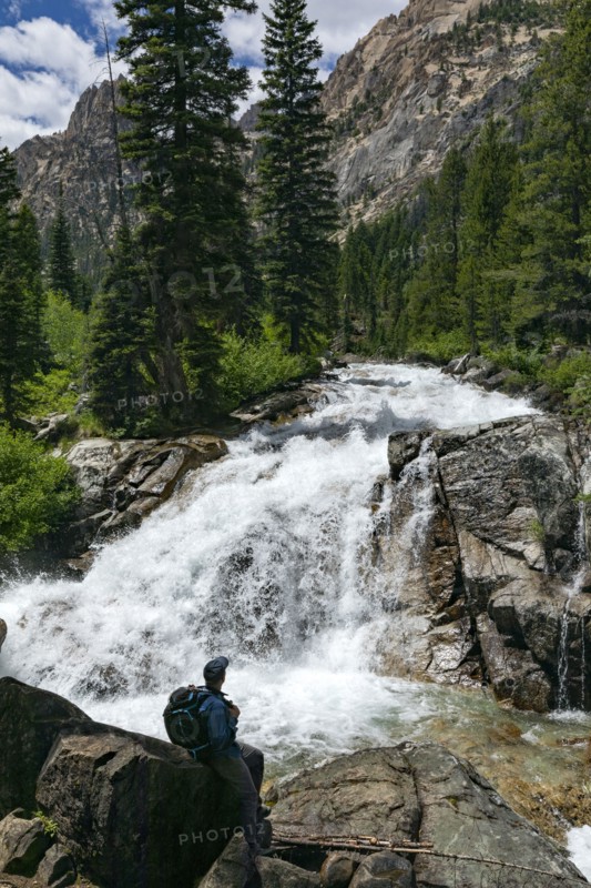 Man hiking by mountain waterfall