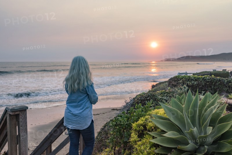 Woman watching sunset from bluff above beach