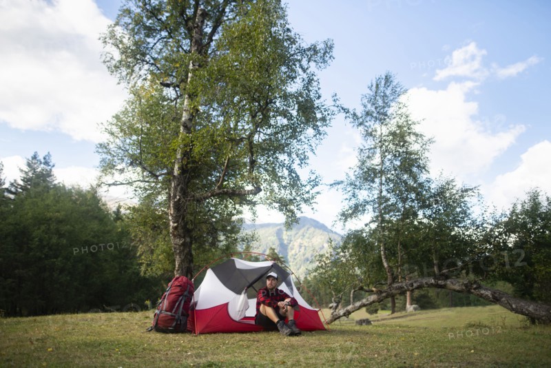 Hiker sitting by tent in mountains