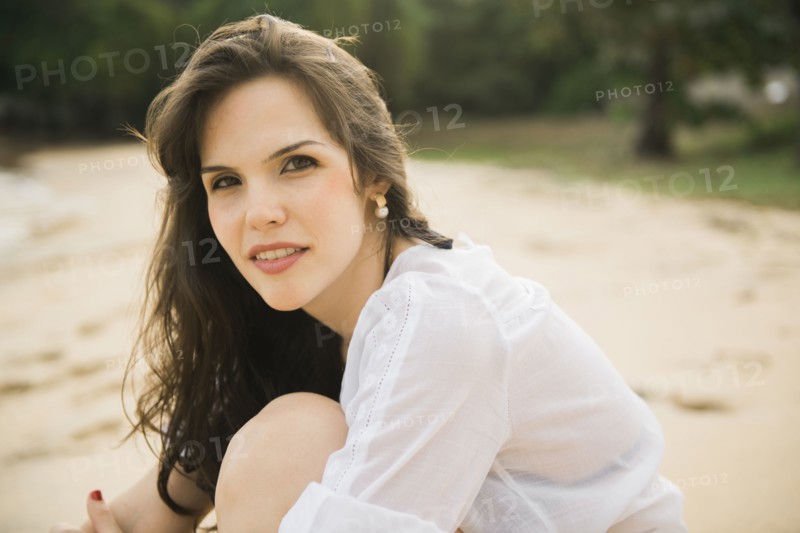 Smiling Caucasian woman sitting on beach
