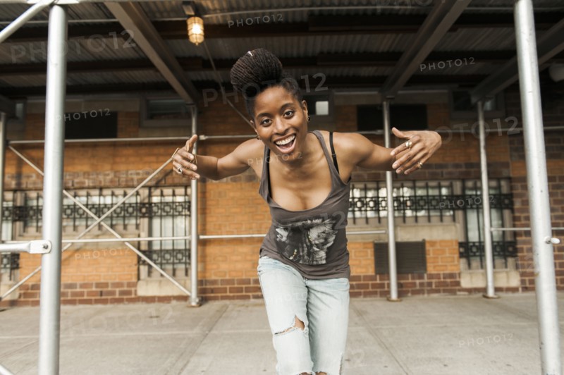 Smiling African American woman dancing under scaffolding