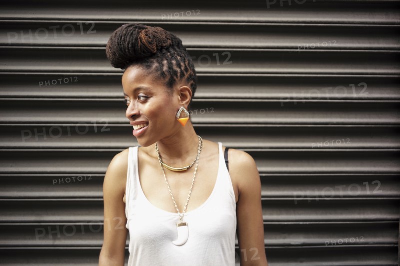 Portrait of smiling  of African American woman with braids near metal wall