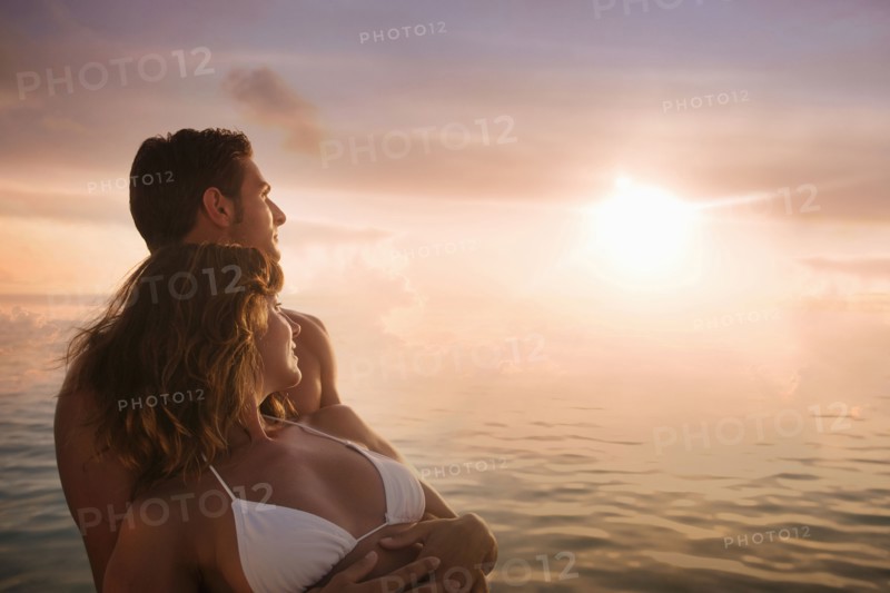 Caucasian couple admiring sunset over ocean