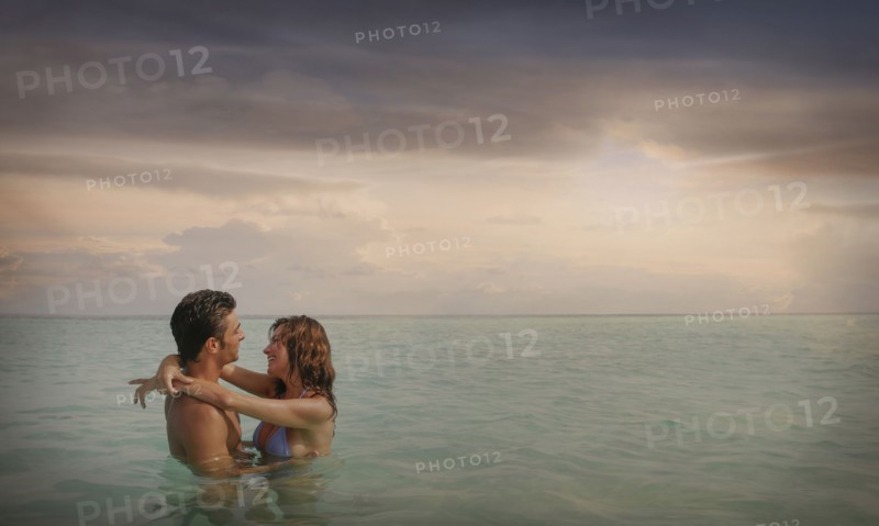 Caucasian couple swimming and hugging in ocean