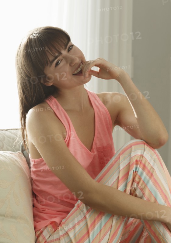 Caucasian woman wearing pajamas smiling on sofa