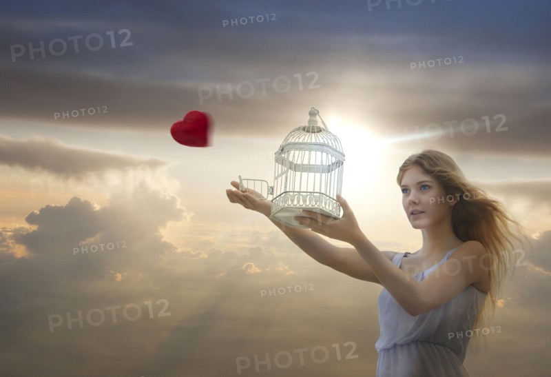 Caucasian woman releasing heart from birdcage