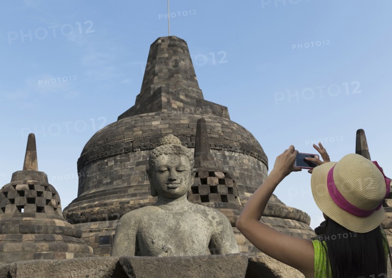 Tourist photographing Buddha statue on Temple of Borobudur
