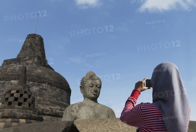 Tourist photographing Buddha statue on Temple of Borobudur