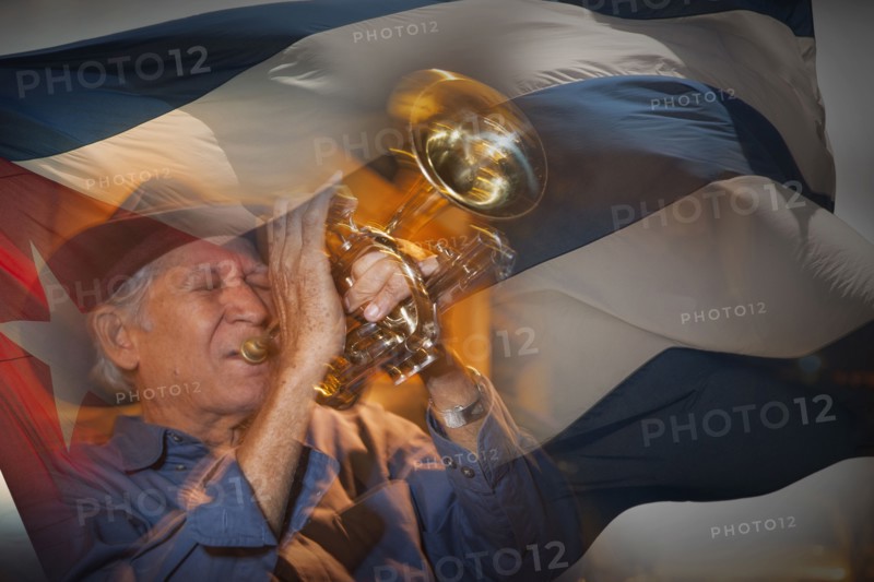 Double exposure of Hispanic musician playing trumpet in front of Cuban flag