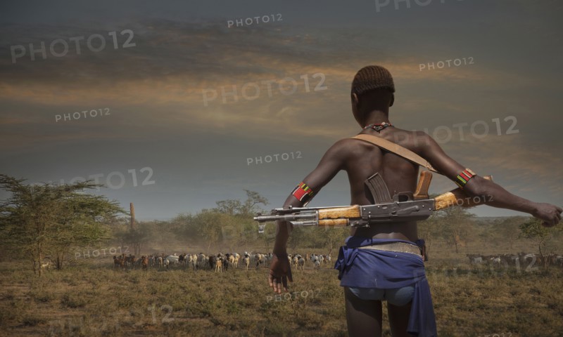 Black soldier carrying gun in open field