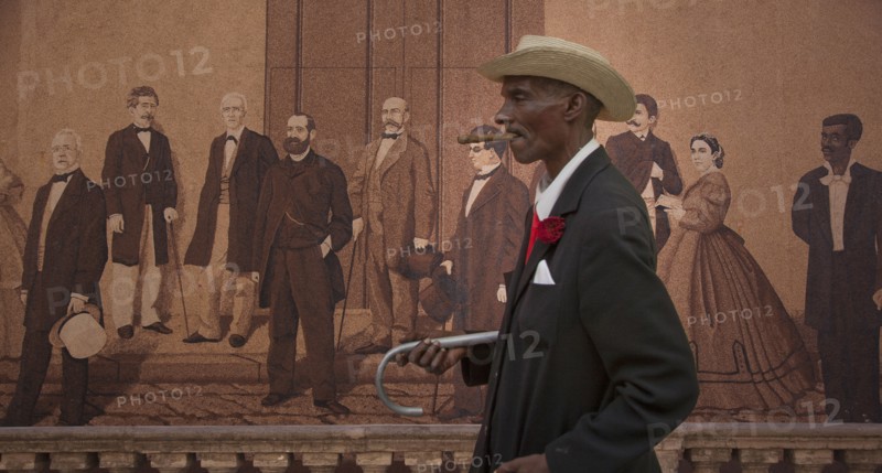 Hispanic man walking past mural