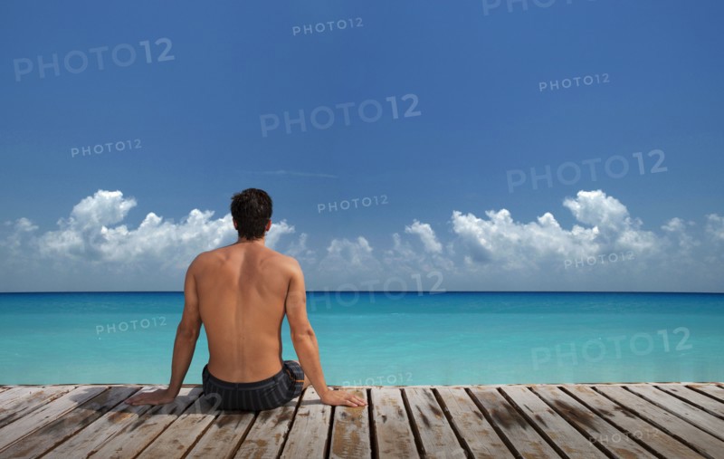 Caucasian man sitting on wooden dock at ocean