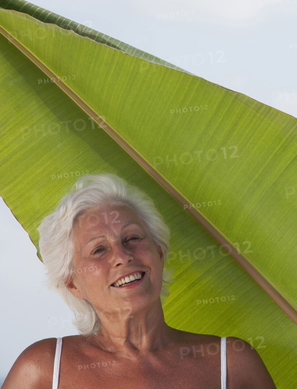 Older Caucasian woman standing under leaf