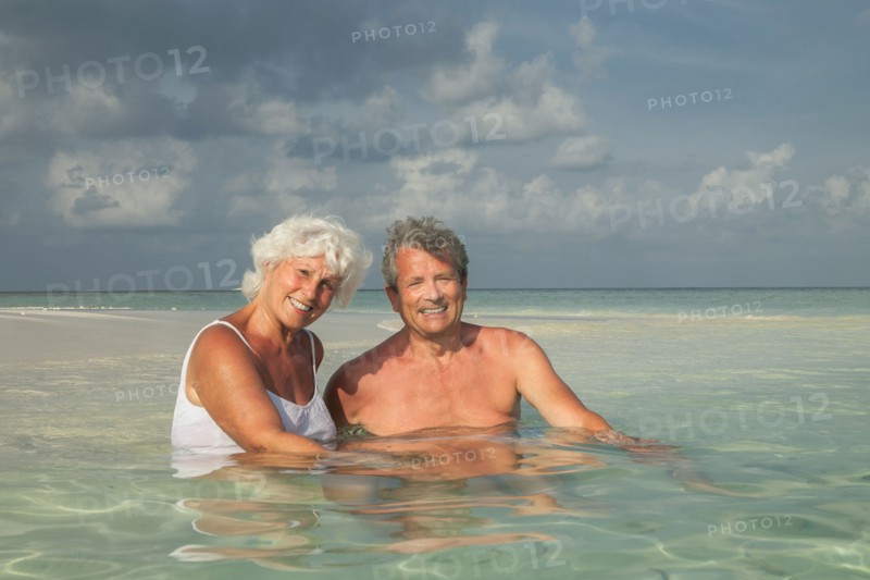 Older Caucasian couple swimming on beach