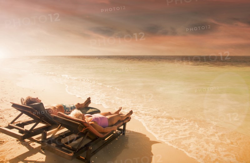 Older Caucasian couple relaxing on beach at sunset