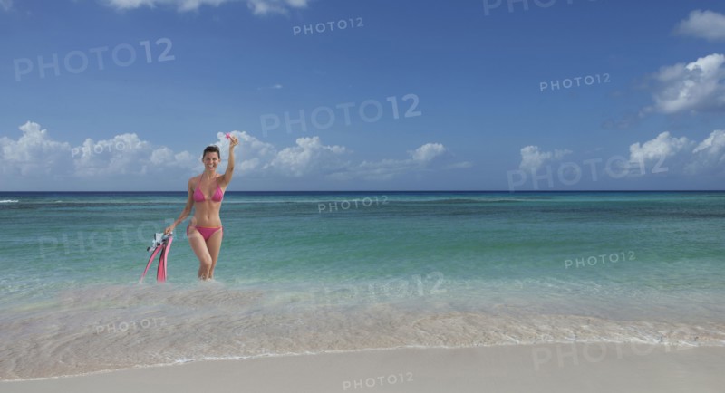 Caucasian woman wading on beach with flippers and snorkel