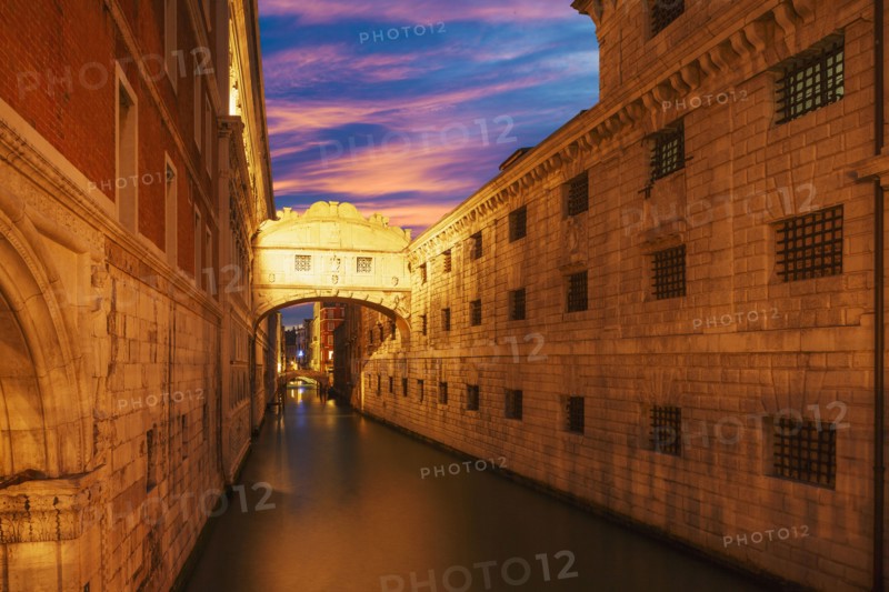 Bridge over Venice canal under sunset sky