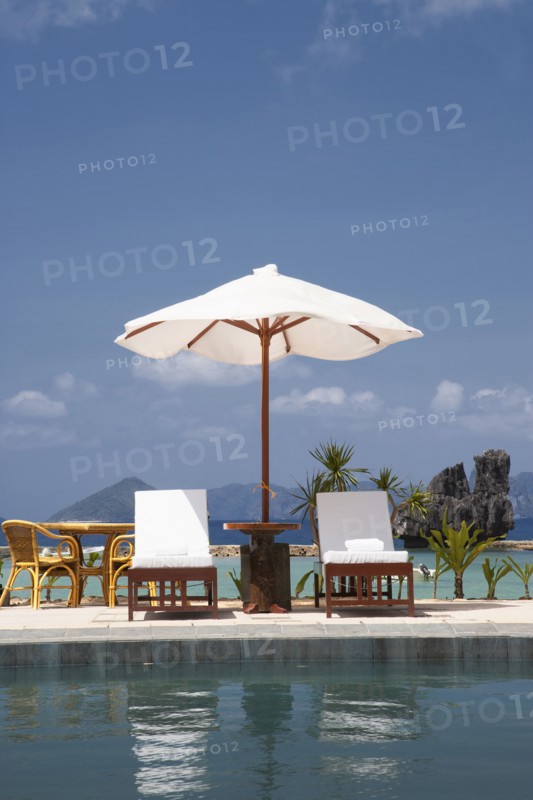 Lawn chair and umbrella at swimming pool
