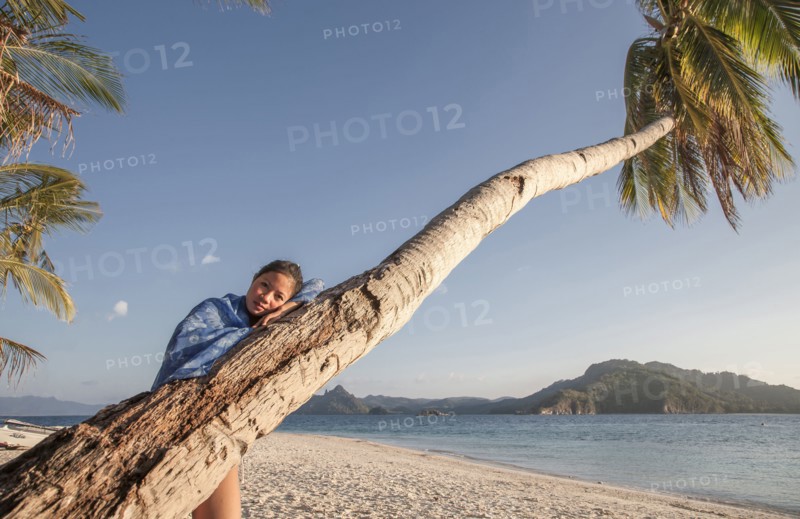 Asian woman on palm tree on beach